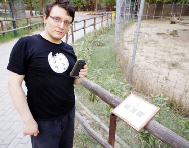 Bojan, wearing a Wikipedia T-shirt, checking a QR code on an information plaque.