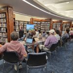 Students present to a group of new editors seated within the Auckland Museum library